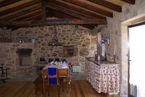 a kitchen with a table and a stone wall at Casa Maria da Assunção in Vila Nova de Cerveira