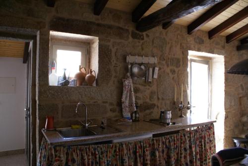 a kitchen with a sink and a stone wall at Casa Maria da Assunção in Vila Nova de Cerveira