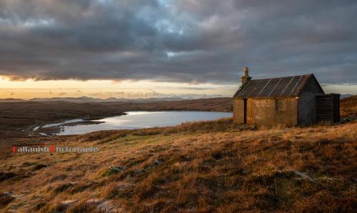 an old house on a hill with a lake at 21 Callanish Luxury Pod in Callernish