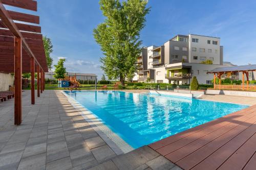a swimming pool with a building in the background at Admiral Luxury Stúdió Apartman By BLTN in Siófok