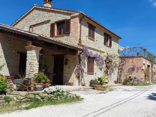 an old brick building with flowers in front of it at Casale San Martino Agriturismo Bio in SantʼAngelo in Pontano