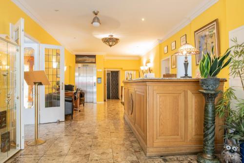 a lobby with yellow walls and a wooden counter at Hotel Kurfürstenhof in Bonn