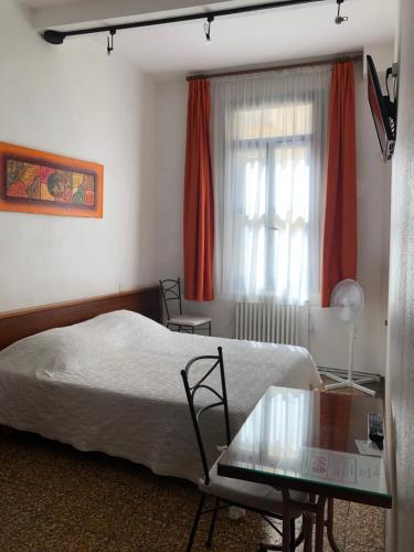 a bedroom with a bed and a table and a window at Hotel des Etuves in Montpellier