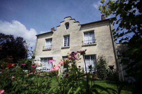 an old stone building with flowers in front of it at Chez Ric et Fer in Coucy-le-Château-Auffrique