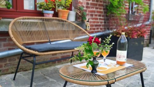 a table with a bottle of wine and a vase with flowers at Chez Ric et Fer in Coucy-le-Château-Auffrique