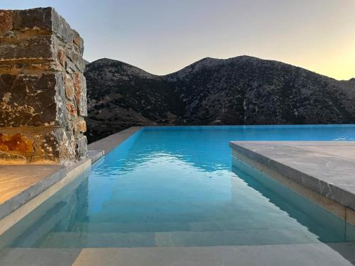 a pool of blue water with mountains in the background at Villa Aires in Vrachasi