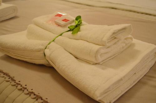 een stapel handdoeken op een bed met een bloem erop bij Il Bisso in Taranto