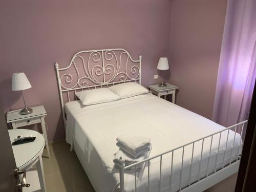 a bedroom with a white bed with two tables and two lamps at Christi Apartments Α&Β in Kokkíni Khánion