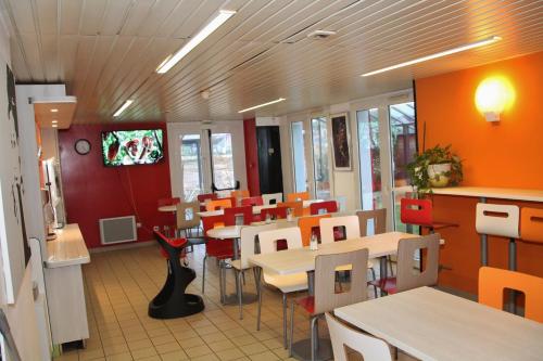 un restaurante con mesas, sillas y TV en Fasthotel Montereau - Esmans, en Esmans