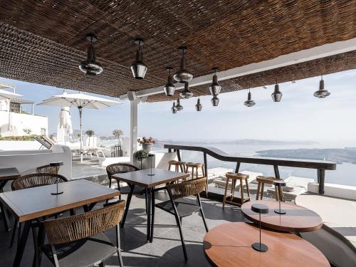 a restaurant with tables and chairs and a view of the ocean at On The Rocks - Small Luxury Hotels of the World in Imerovigli