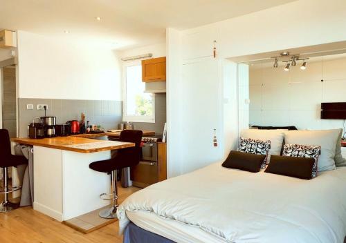 une petite chambre avec un lit et une cuisine dans l'établissement Loueurdappart - Studio Cosy, Très jolie Vue Mer, Tout à pied à la Baule, à La Baule
