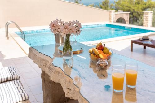a table with a bowl of fruit and glasses of orange juice at Seafront Villa Endless View in Blato