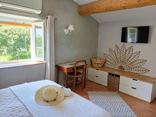 a bedroom with a bed and a desk with a hat on it at La Ferme Les Eybrachas in Réauville