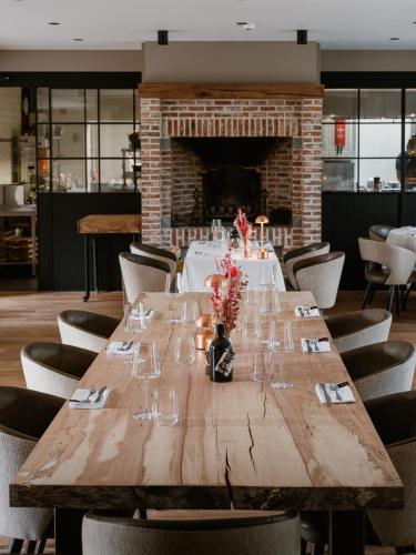 a long wooden table in a restaurant with a fireplace at Ferme d'Ecavéé in Celles