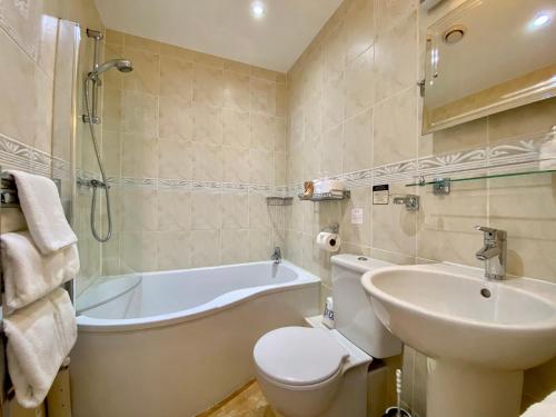 a bathroom with a tub and a toilet and a sink at Crow How Country Guest House in Ambleside