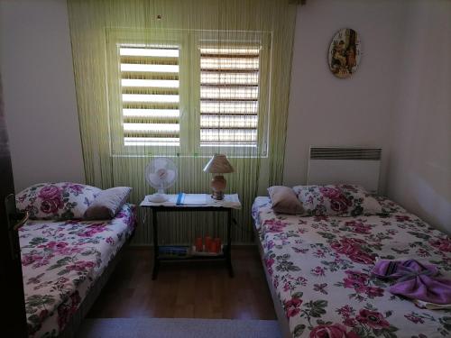 a bedroom with two beds and a table with a lamp at Apartman" Ruža" in Višegrad