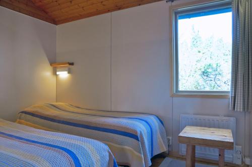 two beds in a room with a window and a table at Isakssons Cottage 6 in Föglö
