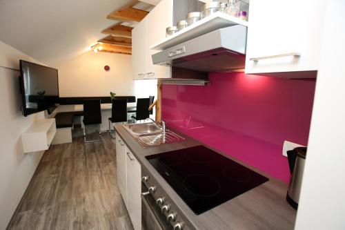 a kitchen with a pink accent wall in a room at Apartments Klemenčič in Bohinj