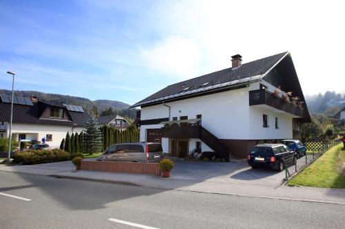 a white house with cars parked in front of it at Apartments Klemenčič in Bohinj