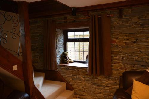 ein Zimmer mit einem Fenster mit einem Hund, der auf einem Fensterbrett sitzt in der Unterkunft Luxurious Self Catering Holiday Cottage Cornwall in Menheniot