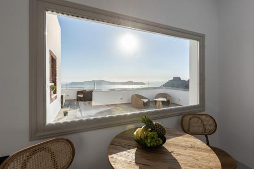 a room with a table with a large window at Suenos De Vida Lux Suite in Firostefani