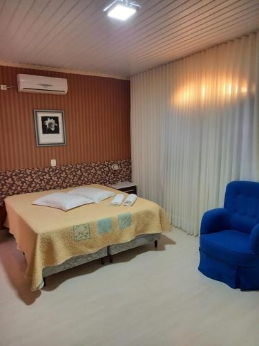 a bedroom with a bed and a blue chair at Nova Vicenza Hotel in Farroupilha