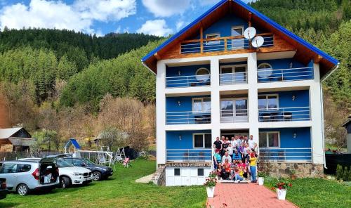 a group of people standing outside of a blue building at Pensiunea Aurelia in Bicaz Chei