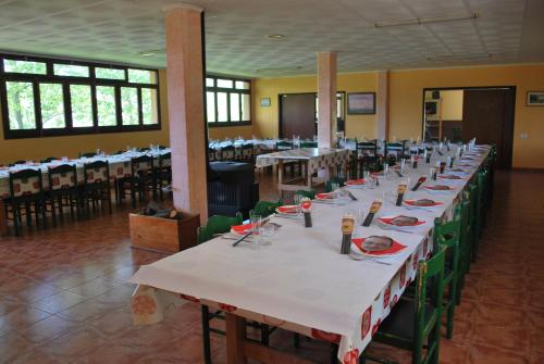 una larga fila de mesas en un salón de banquetes en Casa de colònies La Cadamont, en Sant Joan les Fonts