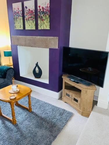 a living room with a fireplace and a tv at Selston House, 3 bedroom cosy cottage Home for up to 6 Guests, Cul-de-sac on Private road in Nottingham