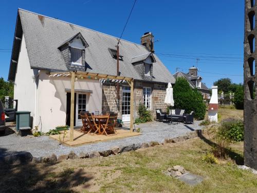 a house with a wooden table in front of it at La Jolie Petite Maison for groups 1-5 in Fontenermont