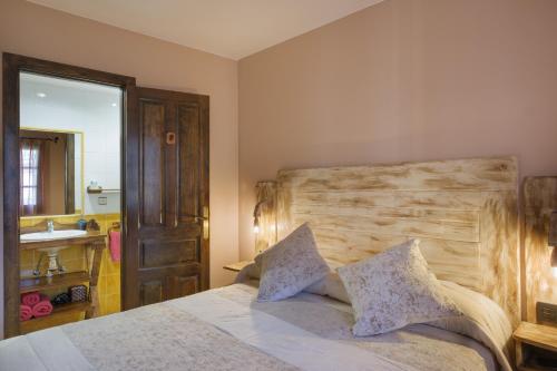 a bedroom with a bed with a wooden headboard and a sink at El Rincón de Andrea Habitaciones in Biescas