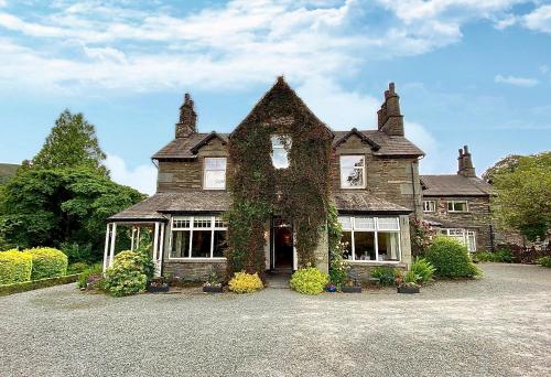 an old stone house with ivy growing on it at Crow How Country Guest House in Ambleside