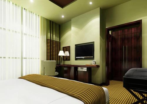 a bedroom with a bed and a desk and a television at Aldar Hotel in Sharjah