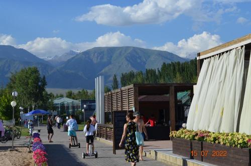 a group of people walking down a sidewalk with mountains in the background at Иссык-Куль ЦО "Karven Four Seasons" таунхаус in Chon-Sary-Oy