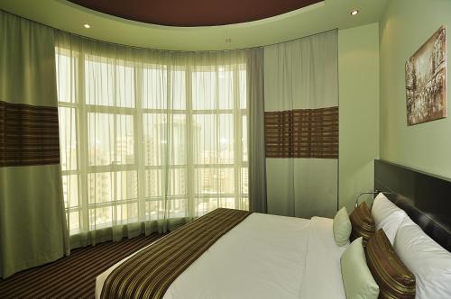 a bedroom with a bed and a large window at Aldar Hotel in Sharjah