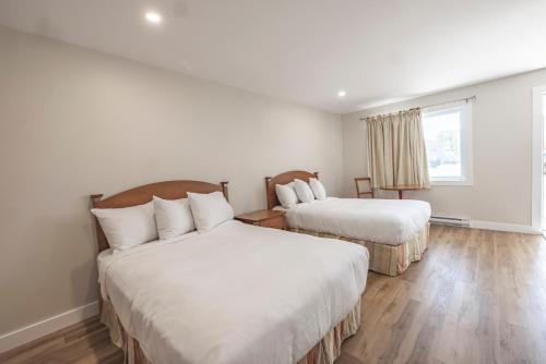 a bedroom with two beds and a window at Le Gaspesiana in Sainte-Flavie
