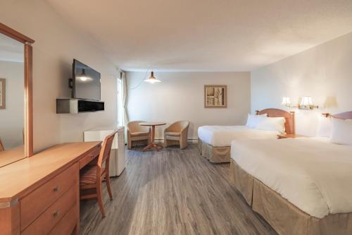 a hotel room with two beds and a desk at Le Gaspesiana in Sainte-Flavie
