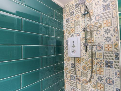 a bathroom with a green tiled wall with a shower at Ty Haf in Haverfordwest