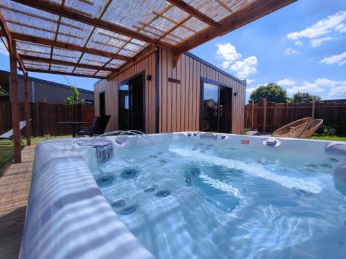 une baignoire jacuzzi dans l'arrière-cour d'une maison dans l'établissement Domaine des graminées, à Jeanménil