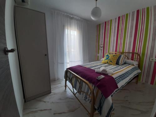 a small bedroom with a bed with a striped wall at Sweet Home in Martos