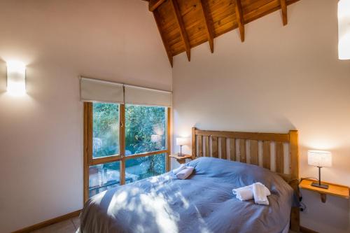 a bedroom with a bed and a large window at Balcones del Sayhueque in Villa La Angostura