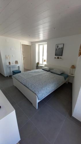 a bedroom with a large bed in a white room at Aloha chambres in Port-Valais