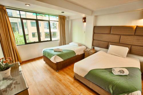 a hotel room with two beds and a window at Inti Tampu Inn in Cusco