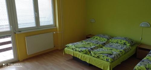 a small bedroom with a bed and two windows at Salatín in Ružomberok