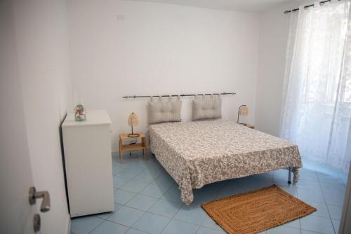 - une chambre blanche avec un lit et un réfrigérateur dans l'établissement ACQUAMARINA APPARTAMENT, à Procida