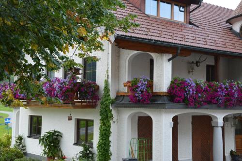 a white house with flowers on the balconies at Pension Zenzlgut in Tiefgraben
