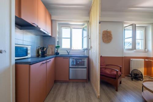 une petite cuisine avec des armoires orange et un évier dans l'établissement HONORÊ SUITE CASAMANCE, à Lyon