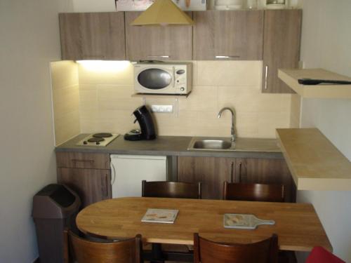 une petite cuisine avec une table et un évier dans l'établissement Grand Studio Hyères Piscine Jardins du Luxembourg 2ème étage, à Hyères