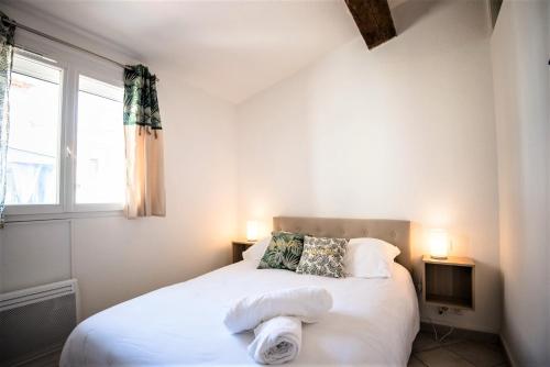 sypialnia z łóżkiem z białą pościelą i oknem w obiekcie Bel appartement cosy au coeur de Cabestany w mieście Cabestany