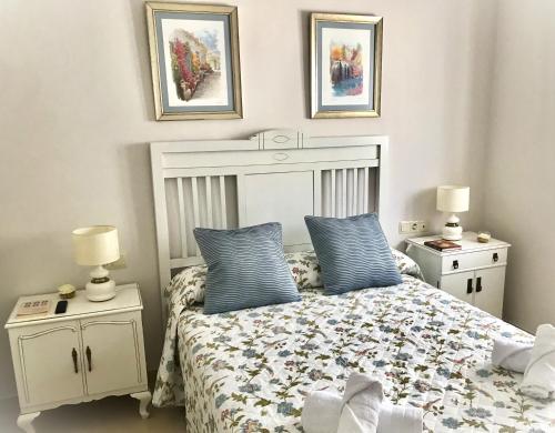 ein Schlafzimmer mit einem Bett mit blauen Kissen und zwei Nachttischen in der Unterkunft Apartamento Las Flores in Ronda